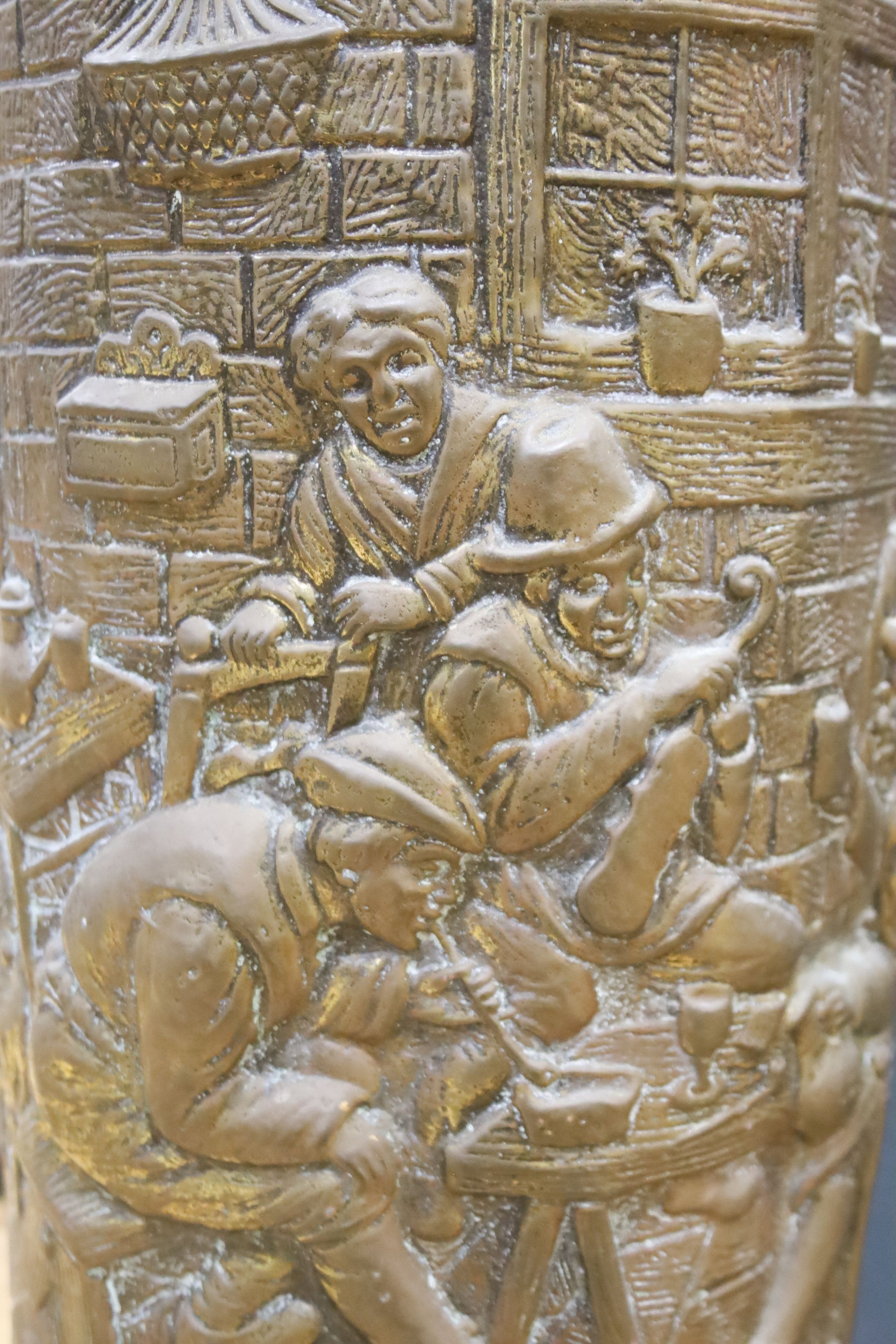 A cylindrical repousse brass stick stand, with walking sticks, parasols, etc.